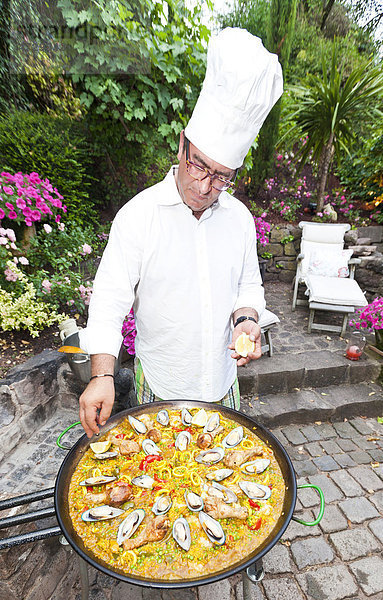 Ein Koch bereitet eine Paella  spanisches Reisgericht  zu  Zugabe von Zitrone  Serie  Nr. 5