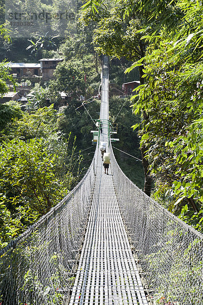 Lange Hängebrücke aus Metall spannt sich über Tal  am Arniko Rajmarg Highway  Nepal  Asien