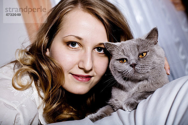 Junge Frau mit Katze im Schlafzimmer