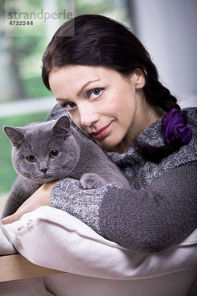 Junge Frau zu Hause mit einer Britischen Kurzhaar-Katze
