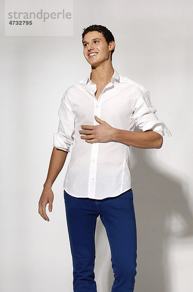 Junger Mann in weißem Hemd und blauen Jeans in Bewegung