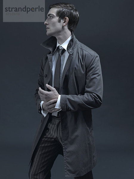 Modeaufnahme eines Mannes im Anzug und Mantel