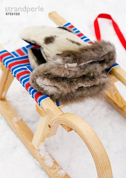 Schlitten mit Handschuhen auf Schnee  Nahaufnahme