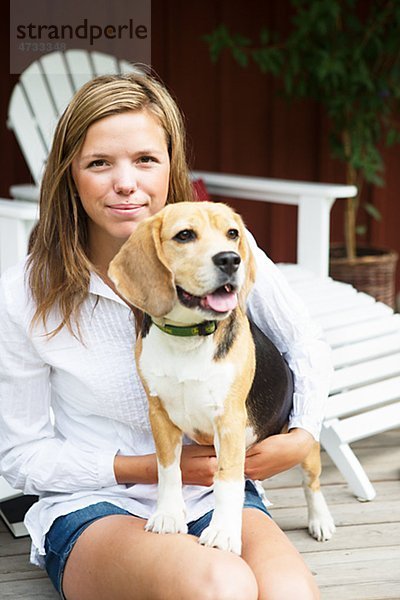 Portrait einer jungen Frau mit Hund auf Veranda