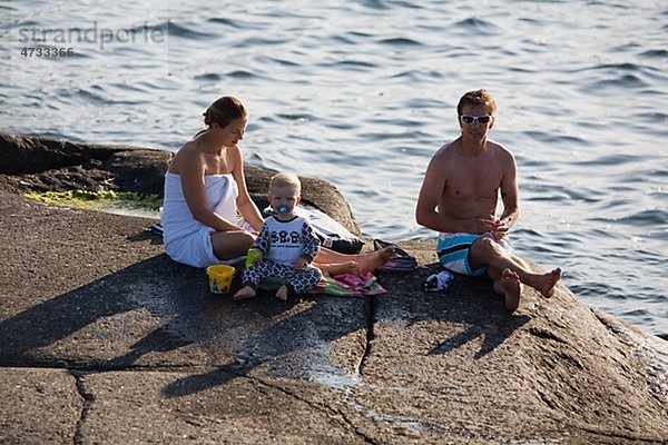 Familie entspannenden auf Felsen auf dem Seeweg