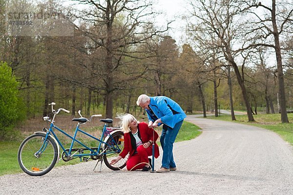 älteres Paar fixieren Tandem-Fahrrad im park