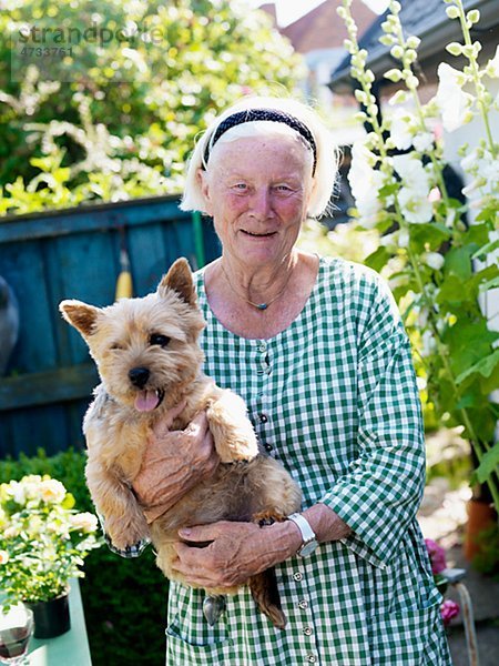 Senior Senioren Portrait Frau halten Hund Garten