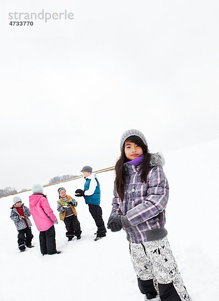 Porträt des Mädchens mit Freunden spielen im Schnee