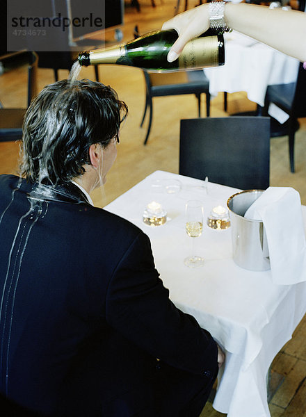 Person pouring Champagne über mans Head im restaurant