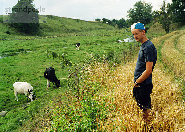 Landwirt stehend auf Feld mit Kühe im Hintergrund