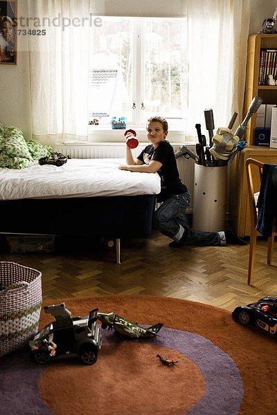 Boy Training mit Hanteln im Schlafzimmer