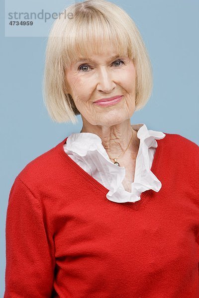 Senior Frau lächelnd vor blauem Hintergrund