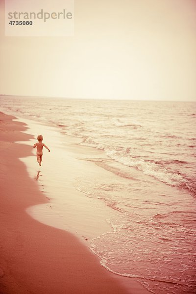 Boy läuft am Strand