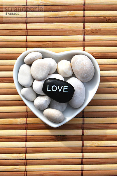 Hot Stone Massagestein mit der Aufschrift Love in herzförmiger Schale aus Porzellan