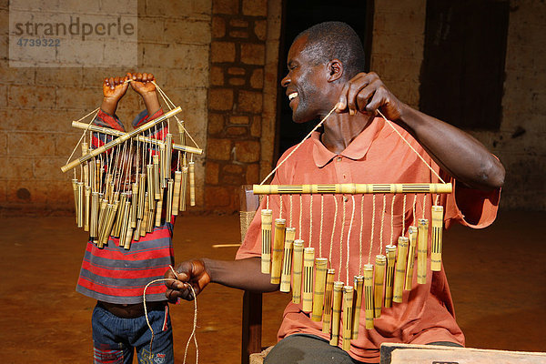 Vater und Sohn bei der Herstellung eines Windspiels aus Bambus  Bafut  Kamerun  Afrika