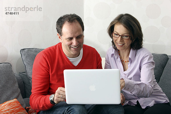Paar  Mann  Frau  Mitte 40  zuhause beim Surfen im Internet am Laptop