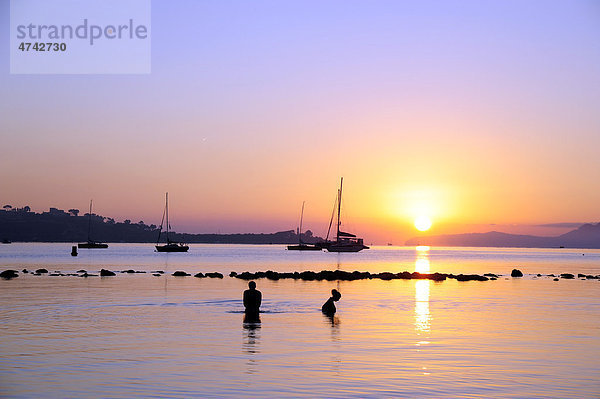 Leute baden bei Sonnenaufgang  Boote in der Bucht von Puerto de Pollensa  Port de Pollenca  Mallorca  Majorca  Balearen  Balearische Inseln  Mittelmeer  Spanien  Europa