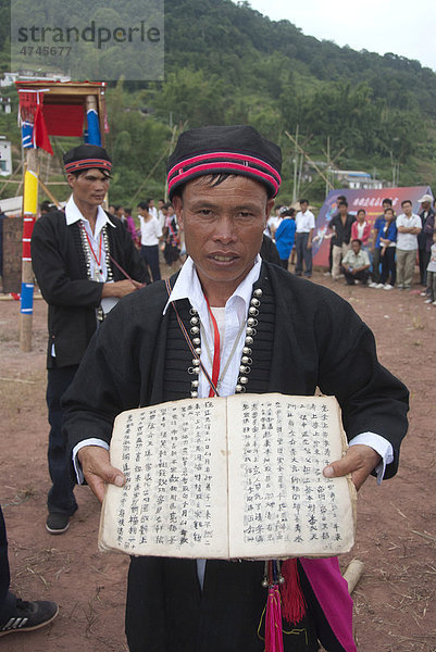 Ethnisches Festival  Mann der Yao Minderheit in Tracht präsentiert Schrift und Buch  Jiangcheng  Stadt Pu'er  Provinz Yunnan  Volksrepublik China  Südostasien  Asien