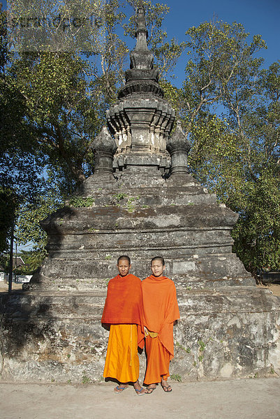Zwei Mönche in orangenen Roben vor einem Stupa  Novizen  Vat Aham  Wat  Luang Prabang  Laos  Südostasien  Asien