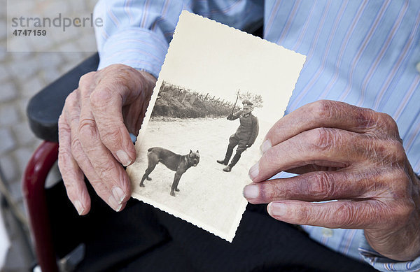Wehrmachtssoldat mit Hund auf einem alten  historischen Foto  alte Hand mit einem schwarzweißen Erinnerungsfoto  Altenheim