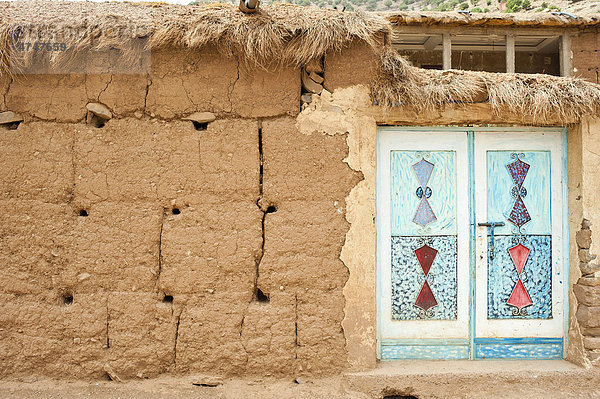 Hauswand aus Stampflehm mit typischer ornamental verzierter und bemalter Haustür aus Blech  Ait Bouguemez-Tal  Hoher Atlas  Marokko  Afrika