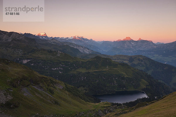Erste Sonnenstrahlen an den Gipfeln der Glarner Alpen mit Garichti Stausee im Tal  gesehen vom Berglimattsee  Kanton Glarus  Schweiz  Europa
