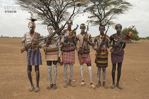 Gruppe Karo Krieger mit Körperbemalung und Gesichtsbemalung mit einem Gewehr über der Schulter  Omo-Tal  Südäthiopien  Äthiopien  Afrika