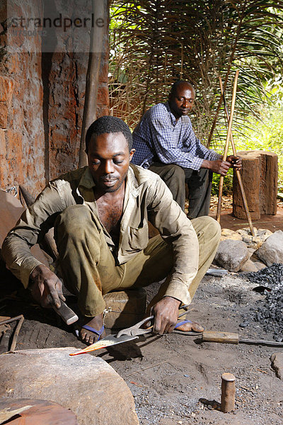 Schmied bearbeitet Altmetall zu Musikinstrument  Mann mit Blasebalg  Babungo  Kamerun  Afrika