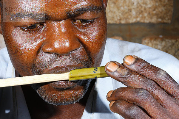 Mann testet Bambuspfeife  Herstellung von Bambuspfeifen  Bafut  Kamerun  Afrika