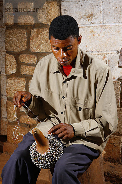 Mann bei der Herstellung von traditionellen Handrasseln  Juju Rattles aus Klebassen  Bafut  Kamerun  Afrika