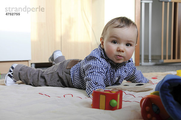 Kleiner Junge  6 Monate  liegt auf dem Bauch auf einer Spieldecke in seinem Kinderzimmer  Deutschland  Europa