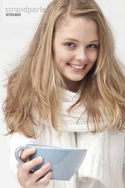 Blonde  weißgekleidete junge Frau  mit hellblauer Teetasse