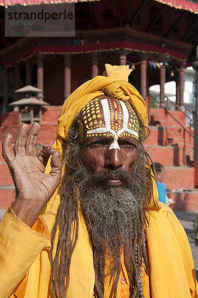 Portrait  heiliger Mann segnet mit der Hand  Mudra  Sadhu  bunt bemalte Stirn  orangefarbenes Gewand  Bart  Hinduismus  Platz Makhan Tole vor Krishna Tempel  auf dem Königsplatz Durbar Square  Kathmandu  Kathmandutal  Nepal  Asien