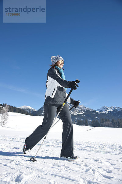 Lächelnde Frau macht Nordic Walking in Winterlandschaft  Tannheimer Tal  Tirol  Österreich