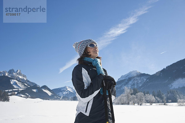 Lächelnde Frau mit Nordic Walking-Stöcken in Winterlandschaft  Tannheimer Tal  Tirol  Österreich
