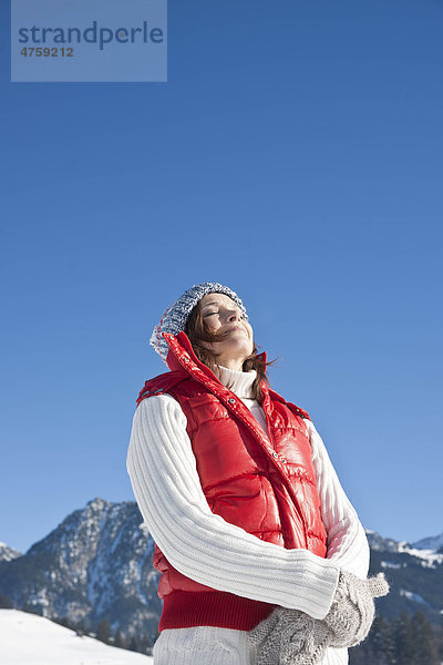 Frau steht mit geschlossenen Augen in Winterlandschaft  Tannheimer Tal  Tirol  Österreich