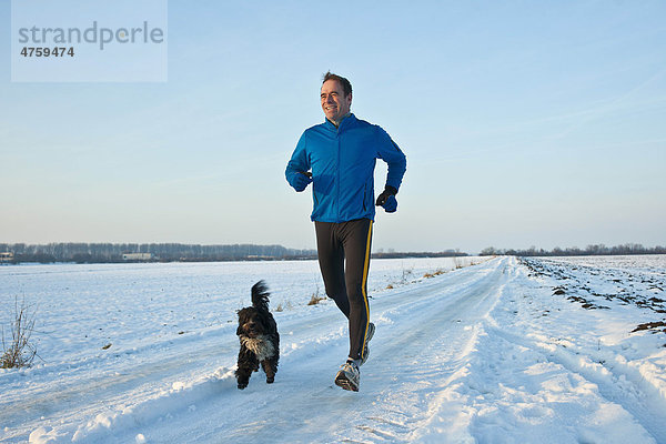 Mann joggt mit Hund im Schnee  Tannheimer Tal  Tirol  Österreich