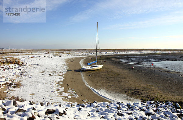 Bucht im Wattenmeer mit Segelboot  verschneiter Strand auf der ostfriesischen Nordseeinsel Spiekeroog  Niedersachsen  Deutschland  Europa