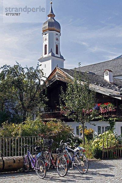 Traditionell bayerisches Wohnhaus mit Balkon und Blumen  dahinter eine Kirche  Garmisch-Partenkirchen  Bayern  Deutschland  Europa