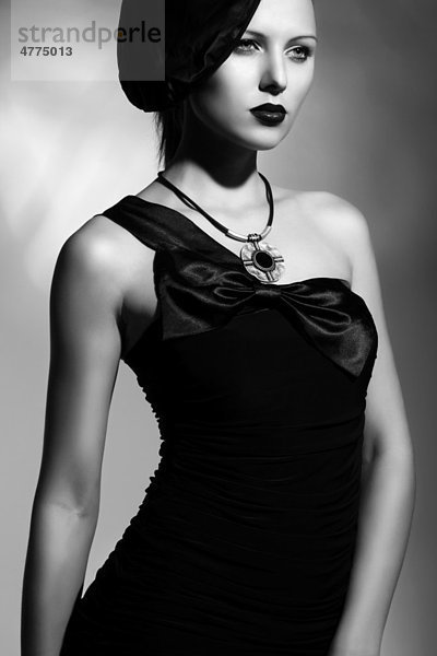 Junge Frau mit eleganter Mütze und schwarzem Kleid  schwarz-weiß