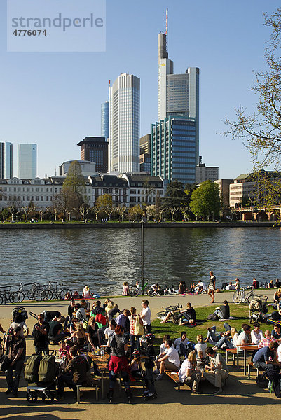 Leute am Mainufer  Schaumain Kai  Museumsufer  dahinter die Skyline vom Büro- und Bankenviertel  Frankfurt am Main  Hessen  Deutschland  Europa