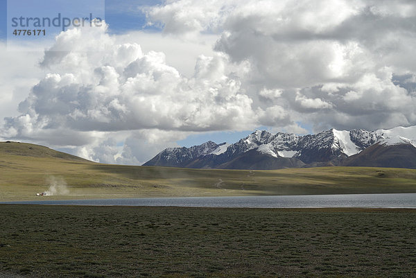 Zwei Trucks begenen sich am Takyel Tso See auf staubiger Piste vor Schneebergen des Himalaya  Changtang Hochebene  Westtibet  Provinz Ngari  Tibet  China  Asien