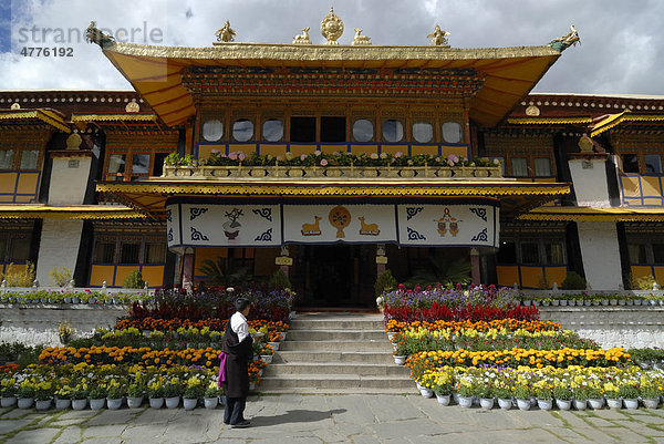 Tibetischer Mann in Tracht steht vor Sommerpalast des Dalai Lama im Norbulingka  Juwelengarten  mit Blumen  Lhasa  Tibet  China  Asien