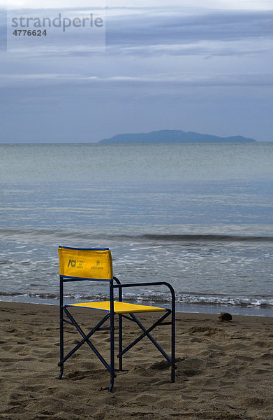 Leerer gelber Stuhl am Strand des Parco Naturale della Maremma  in der Ferne die Insel Giglio  Toskana  Italien  Europa