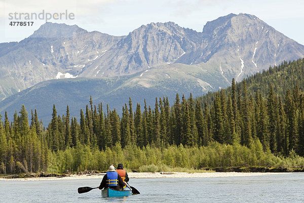 Zwei Männer in einem Kanu  Kanuten beim Paddeln  Kanufahren auf dem Upper Liard River  Pelly Mountains Gebirgszug hinten  Yukon Territory  Kanada
