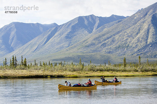 Kanufahrer paddeln auf dem Wind River  Kanus  hinten nördliche Mackenzie Mountains Gebirgskette  Yukon Territorium  Kanada