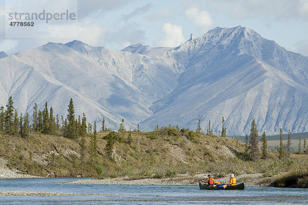 Kanufahrer paddeln auf dem Wind River  Kanu  hinten nördliche Mackenzie Mountains Gebirgskette  Yukon Territorium  Kanada