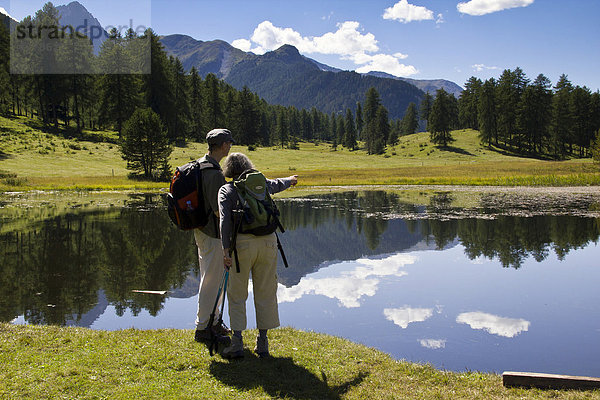 Wanderer in der Hochmoorebene mit dem schwarzen See Lai Nair bei Tarasp und Vulpera  Scuol  Unterengadin  Graubünden  Schweiz  Europa