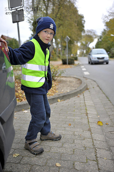 Kleiner Junge mit Leuchtweste will Straße überqueren