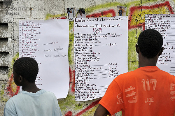 Bewohner betrachten eine Liste von Opfern des Erdbebens von Januar 2010 an einer Hauswand  Stadtteil Fort National  Port-au-Prince  Haiti  Karibik  Zentralamerika